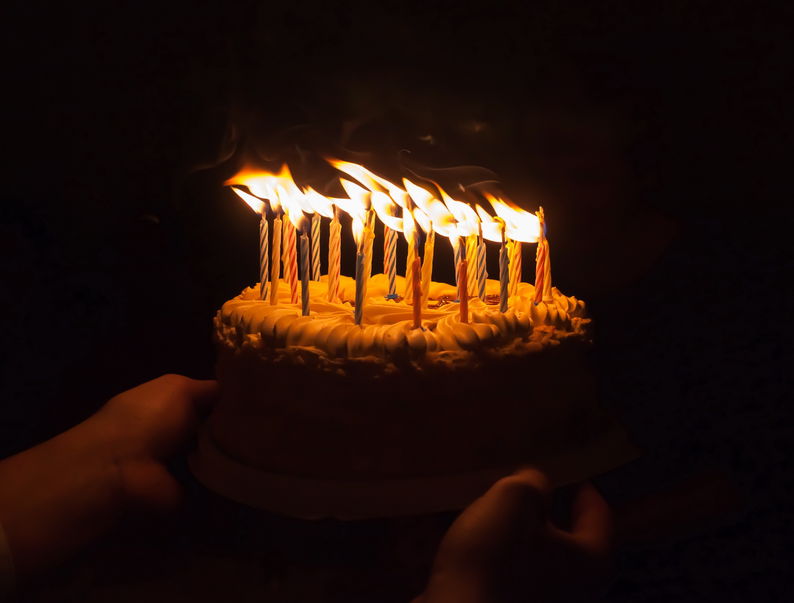 74635011 - anniversary cake with burning candles on dark background ...